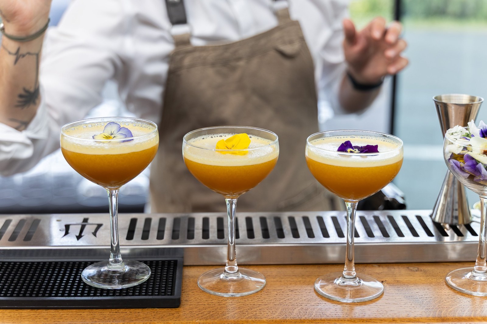 Trois cocktails signature dressés en coupe et décorés d'une fleur comestible