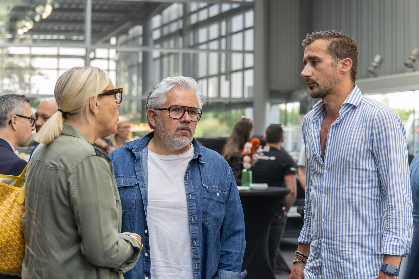 Trois invités d'une soirée Business Comedy Club en conversation, un verre à la main